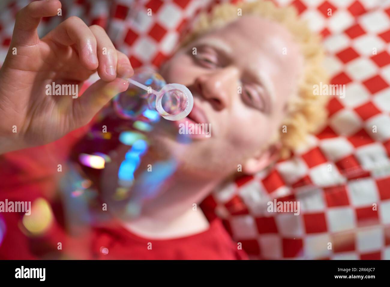 Young man blowing bubbles with bubble wand Stock Photo