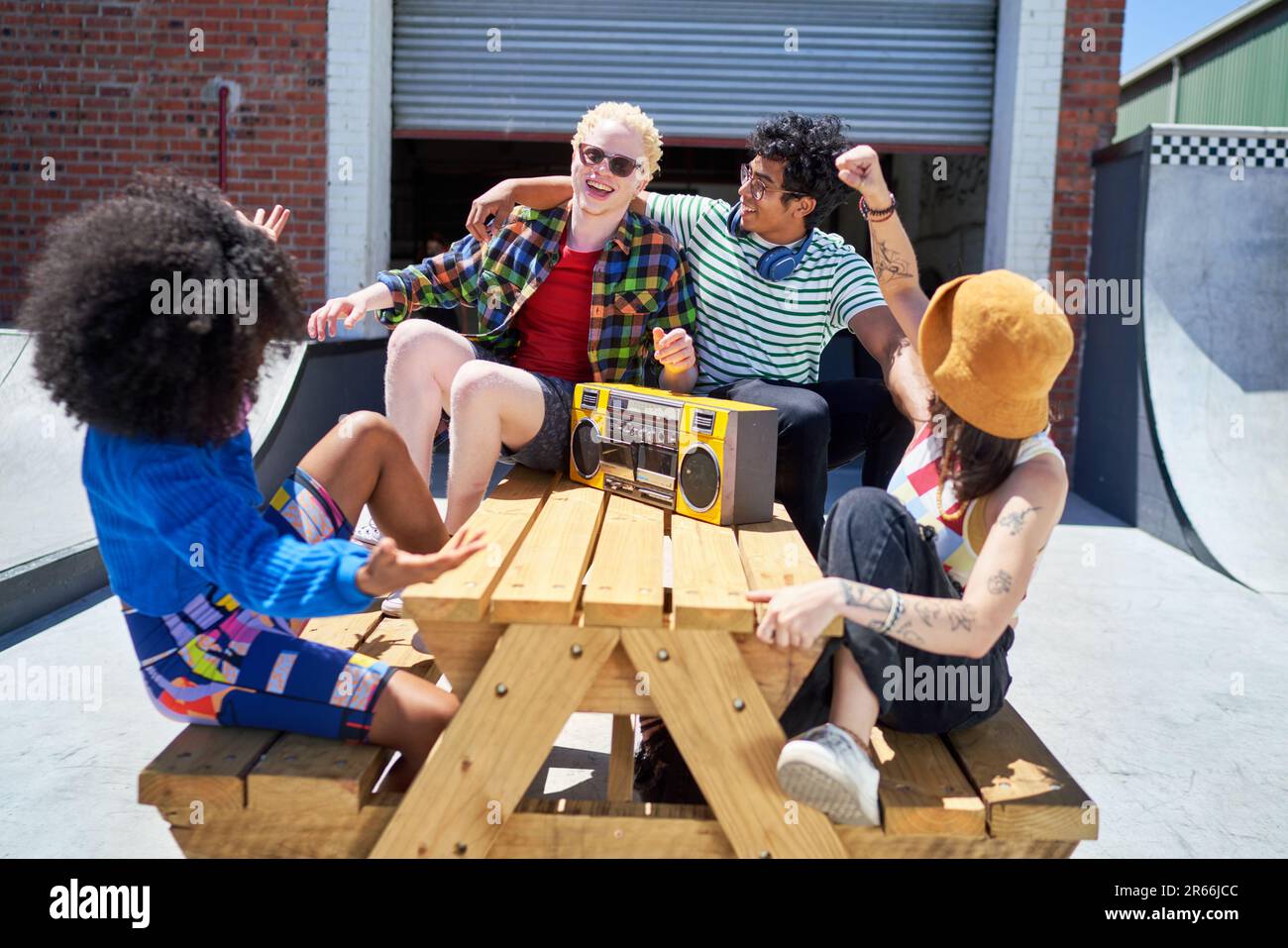 Happy young friends listening to music with boom box at picnic table Stock Photo