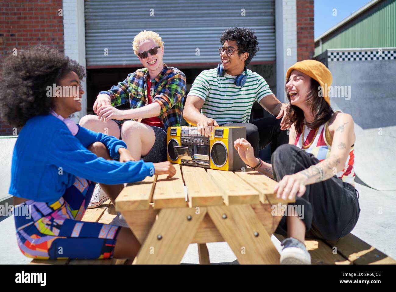 Happy young friends laughing, listening to music with boom box Stock Photo