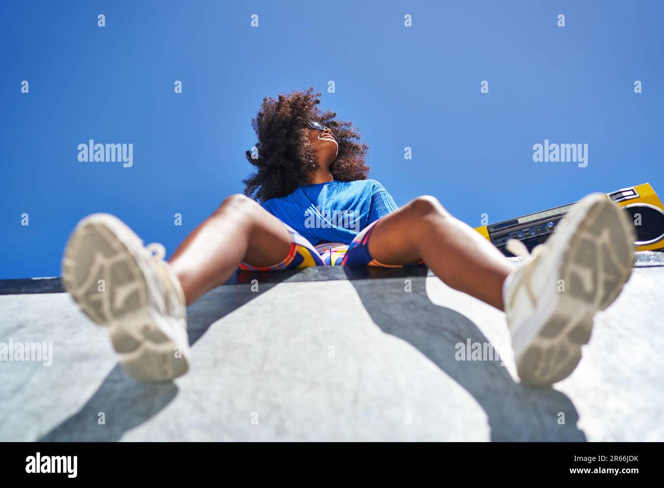 Carefree young woman with boom box at edge of sports ramp Stock Photo