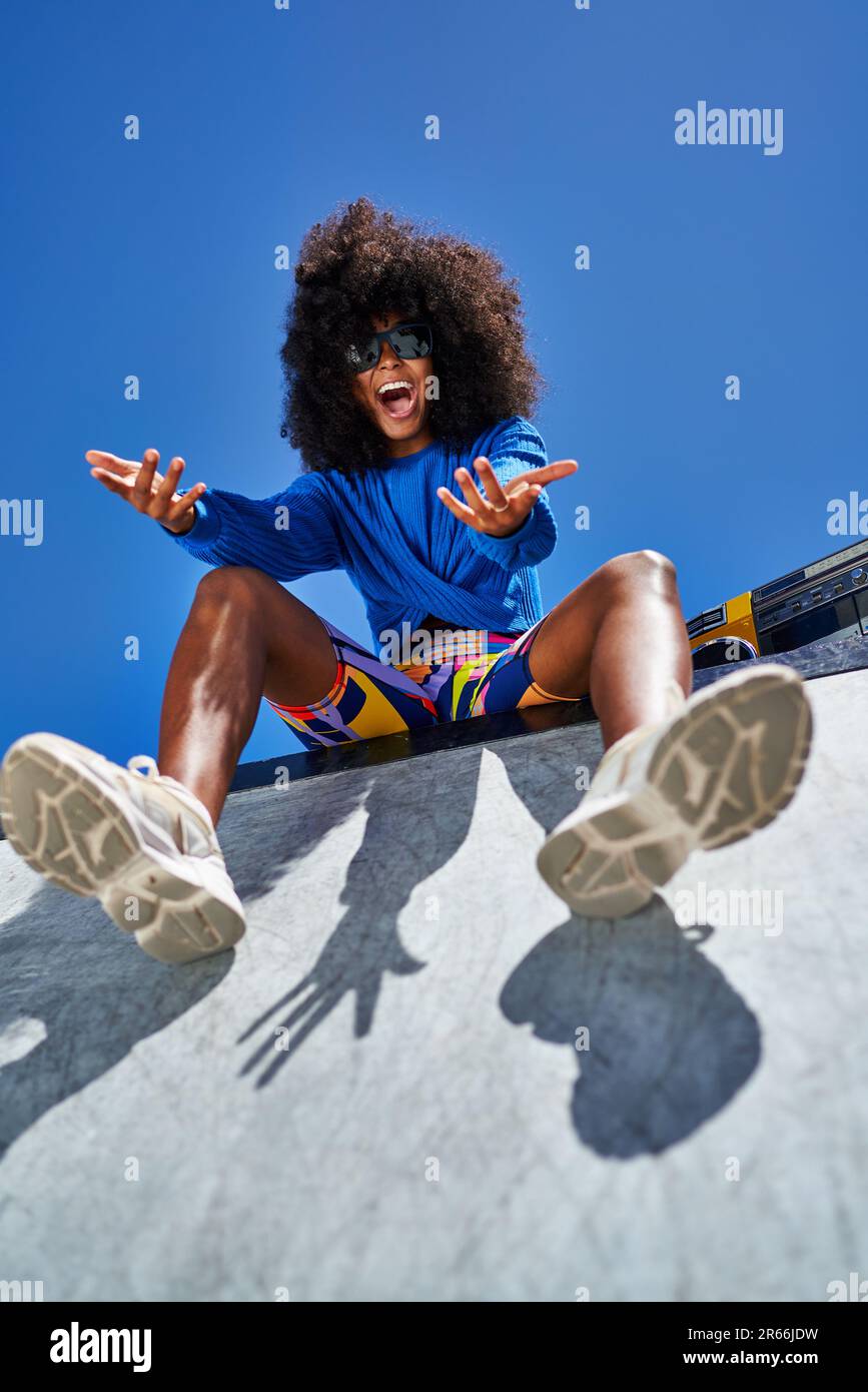 Portrait happy young woman gesturing at sunny sports ramp Stock Photo