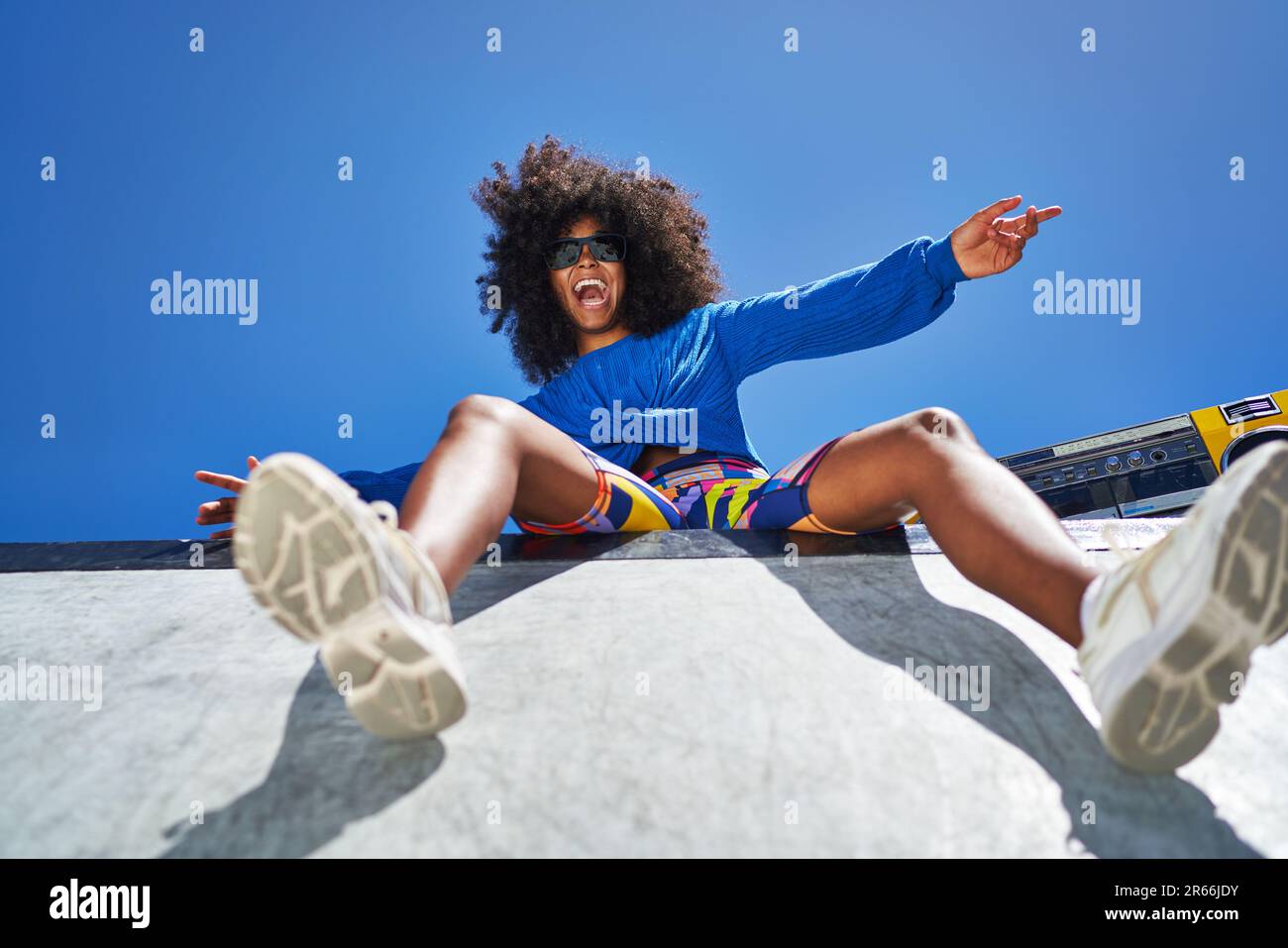 Portrait carefree young woman cheering at sunny sports ramp Stock Photo