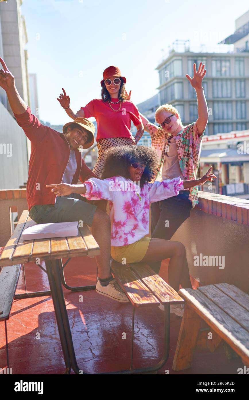 Portrait happy young friends cheering on sunny urban rooftop Stock Photo