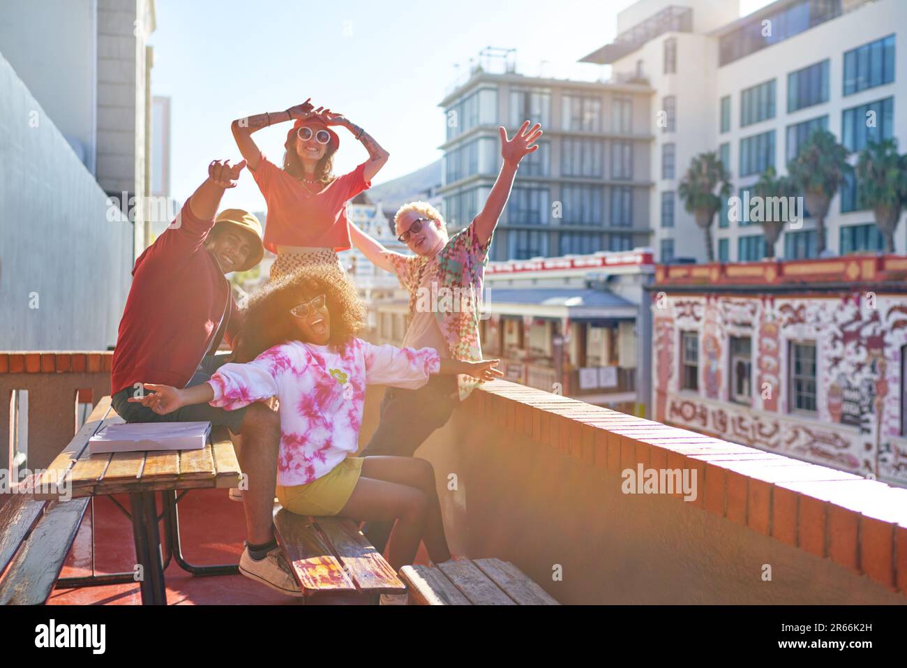 Portrait happy young friends cheering on sunny city rooftop Stock Photo