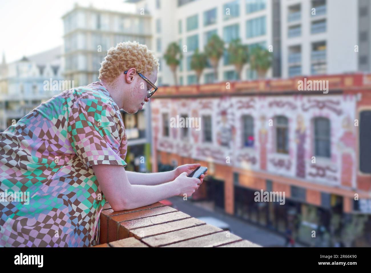 Young man using smart phone on urban balcony Stock Photo