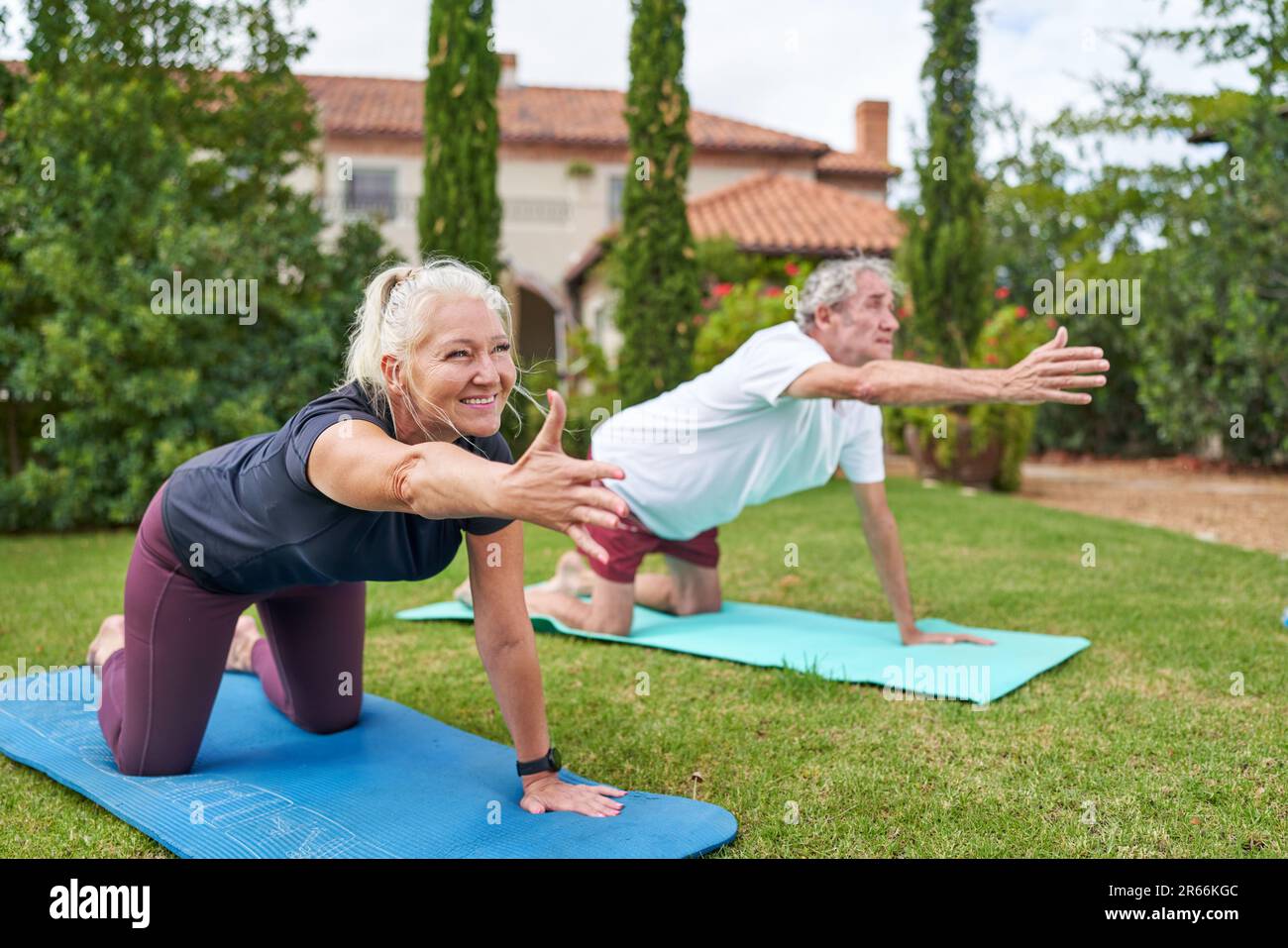 Happy senior couple practicing yoga in villa garden grass Stock Photo