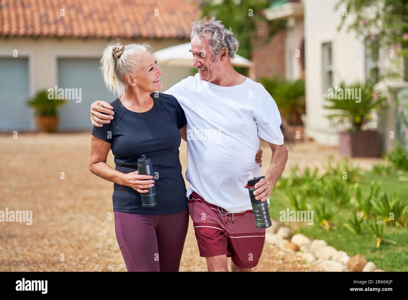 Happy, active senior couple hugging and walking outside villa Stock Photo