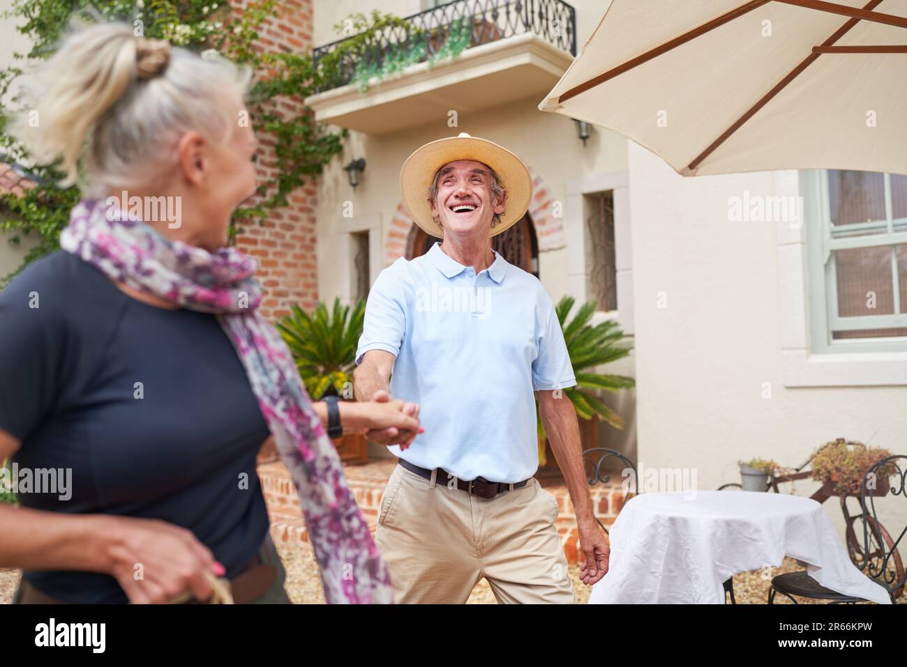 Happy, carefree senior couple dancing outside summer villa Stock Photo