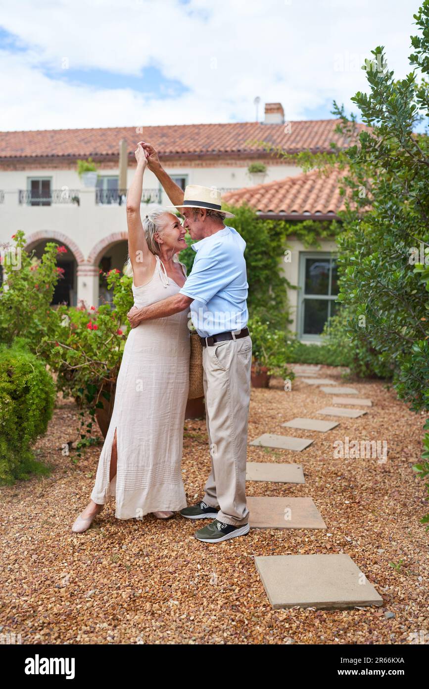 Happy senior couple dancing outside villa in summer garden Stock Photo