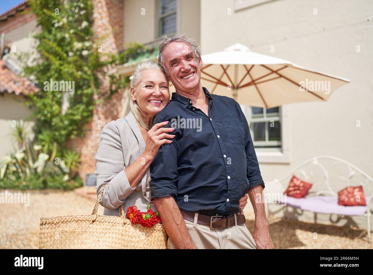 Portrait happy senior couple hugging on sunny summer villa patio Stock Photo