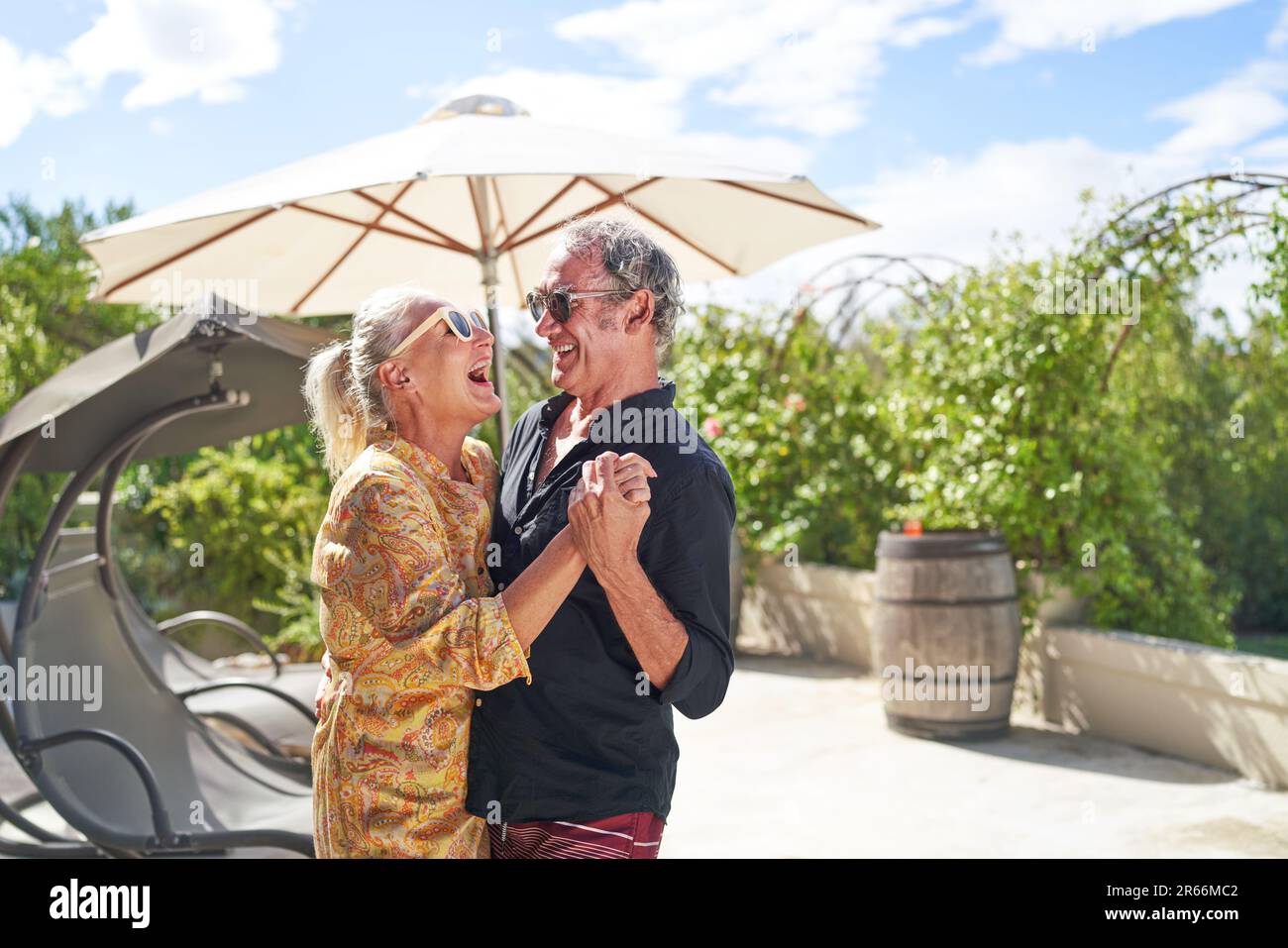 Happy, carefree senior couple laughing and dancing on summer patio Stock Photo