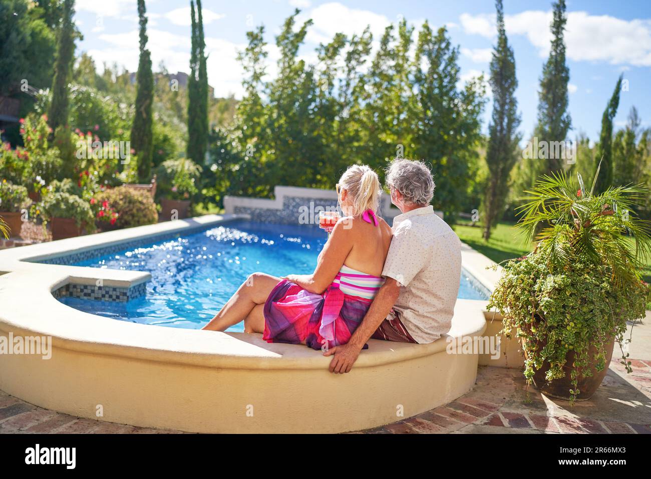 Senior couple relaxing at sunny summer swimming pool Stock Photo