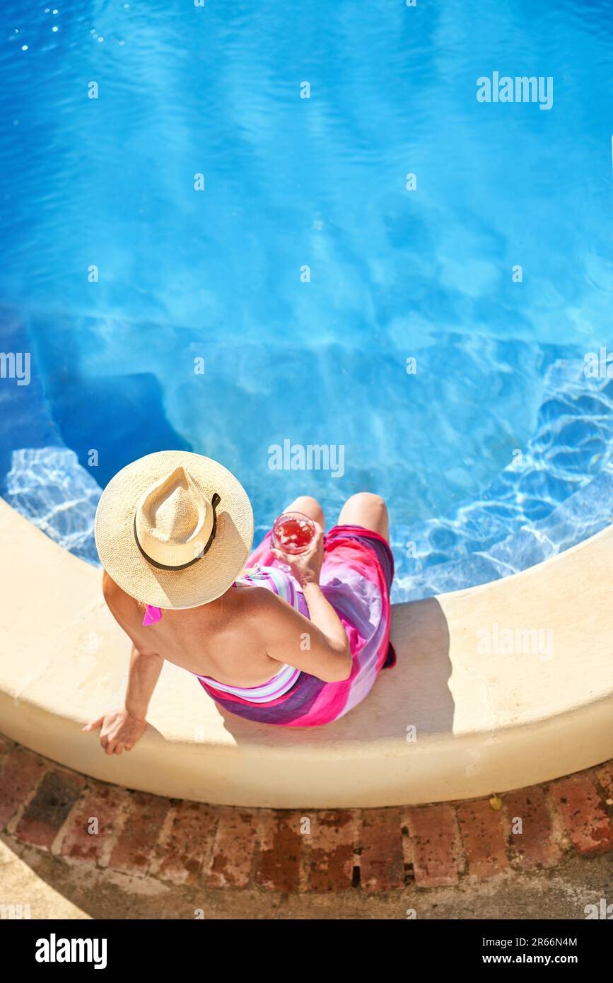 View from above senior woman relaxing at sunny summer swimming pool Stock Photo