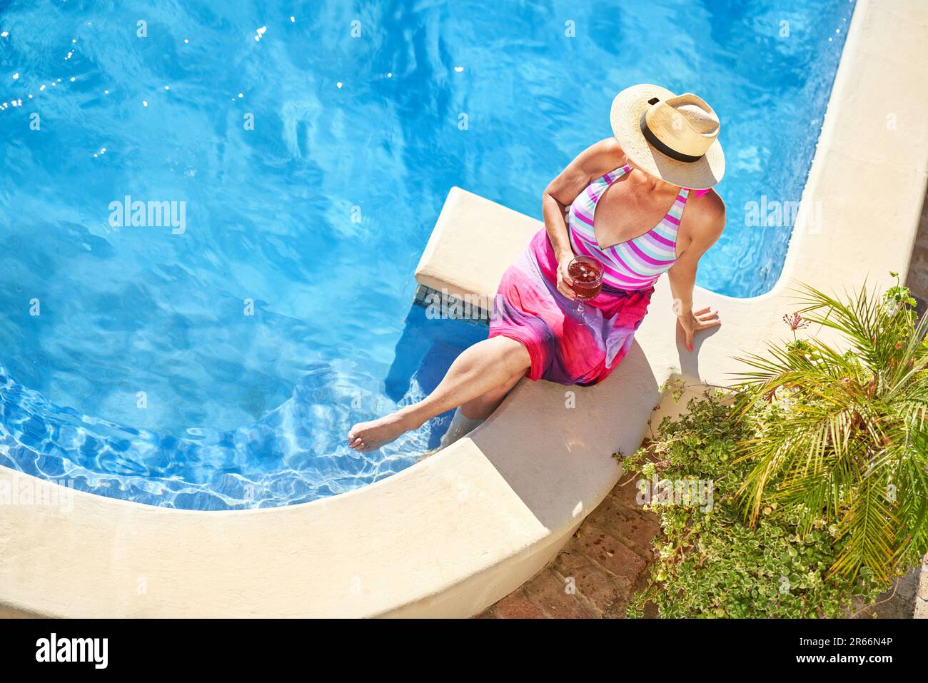 View from above senior woman drinking cocktail at sunny poolside Stock Photo