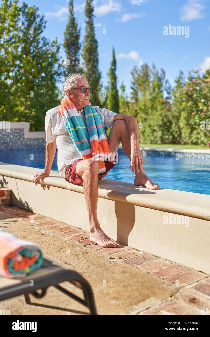 Senior man relaxing at sunny summer swimming pool Stock Photo