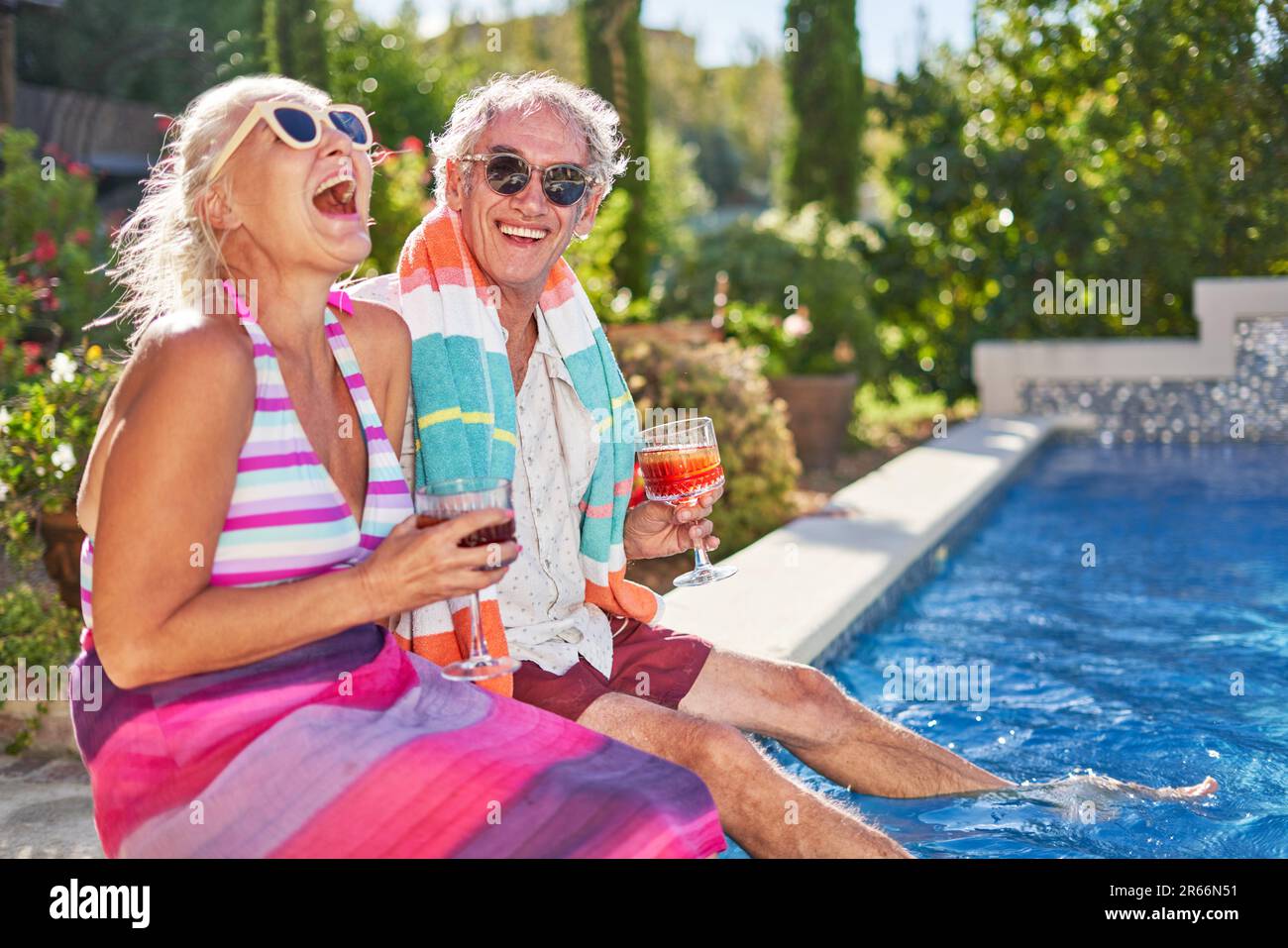 Portrait happy, carefree senior couple laughing at summer swimming pool Stock Photo