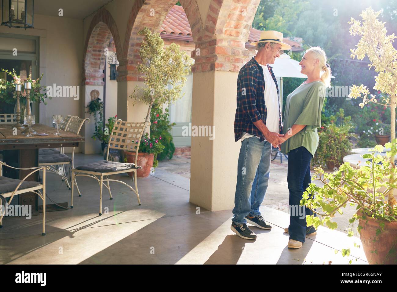Happy senior couple holding hands on sunny villa patio Stock Photo