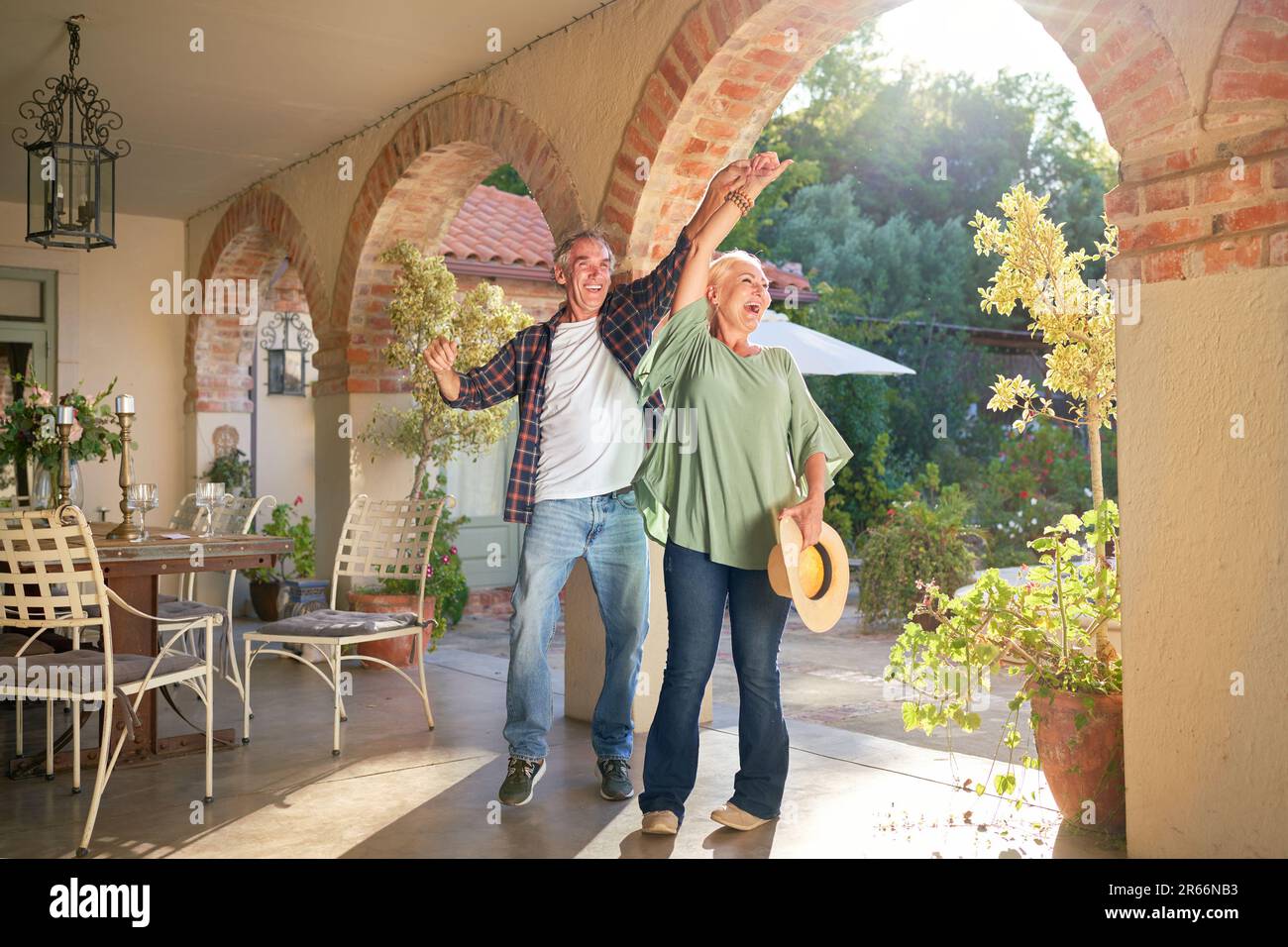 Happy, carefree senior couple dancing on sunny villa patio Stock Photo