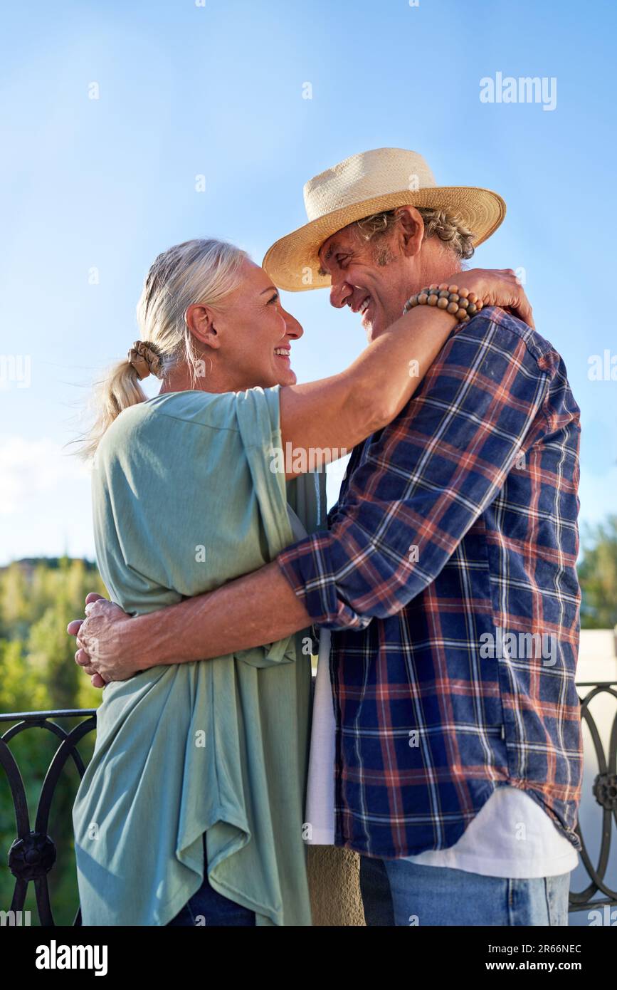 Happy, affectionate senior couple hugging on balcony Stock Photo