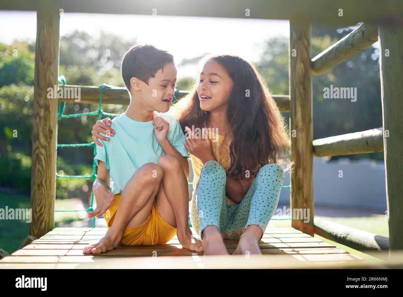 Sister hugging brother with Down Syndrome on playground equipment Stock Photo