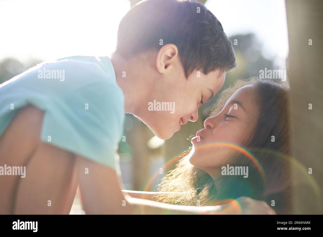 Close up sister kissing cute brother with Down Syndrome in sunshine Stock Photo