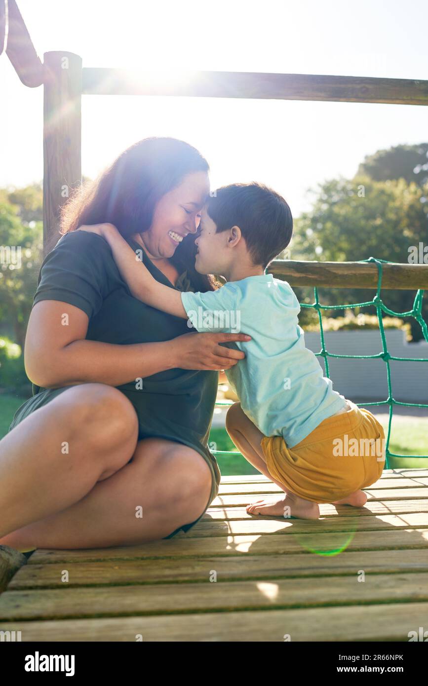 Happy mother and son at sunny playground structure Stock Photo
