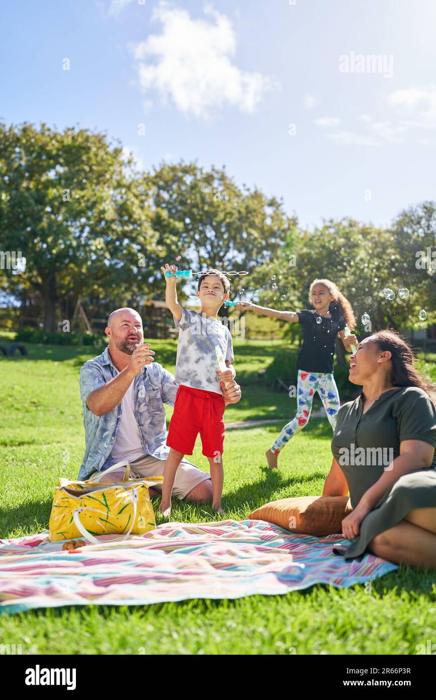 Parents watching happy son with Down Syndrome playing with bubbles Stock Photo