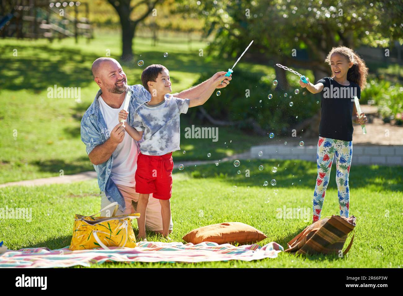 Happy family playing with bubbles in sunny summer park Stock Photo