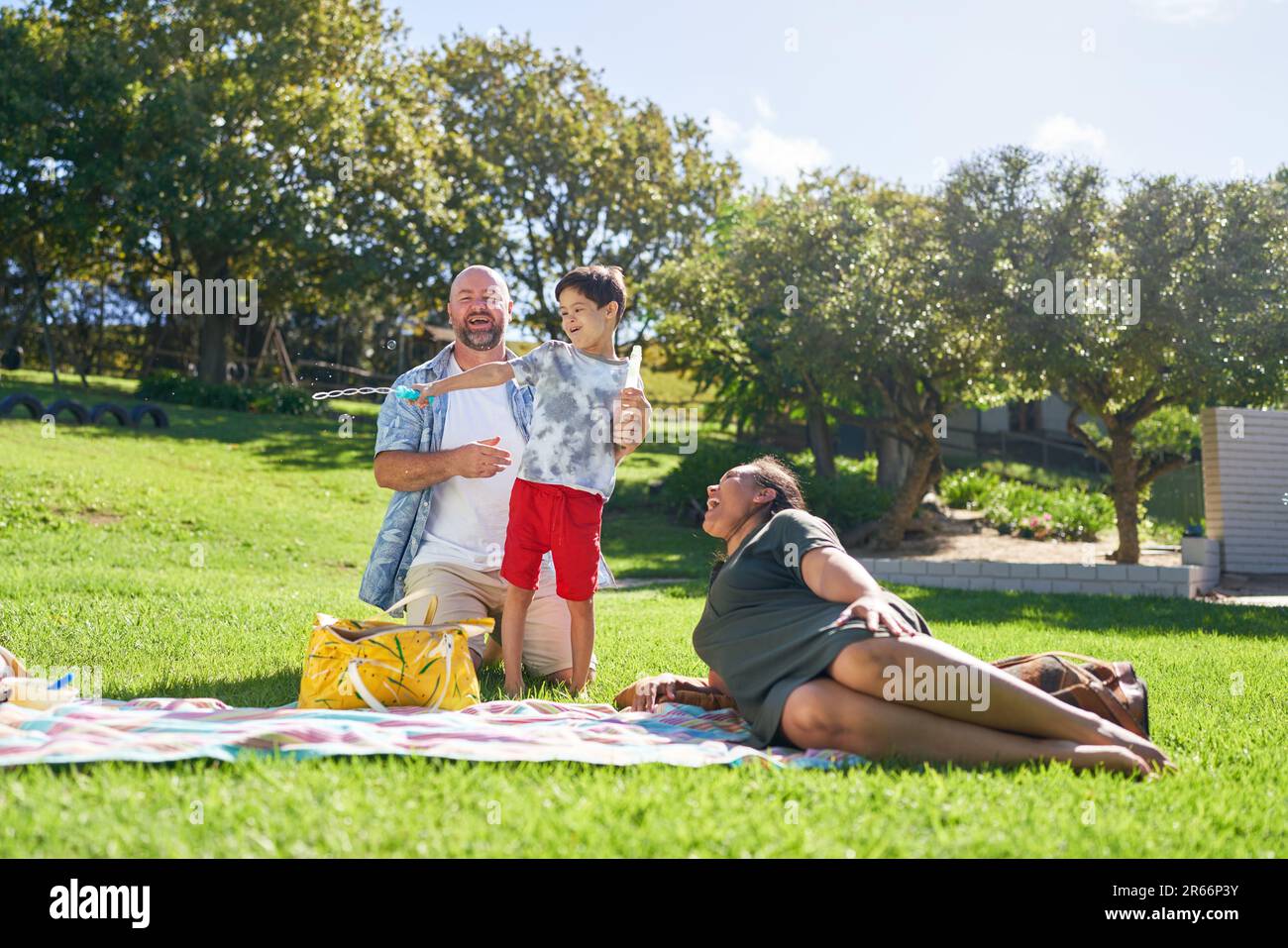 Happy family relaxing and playing with bubbles in sunny summer park Stock Photo