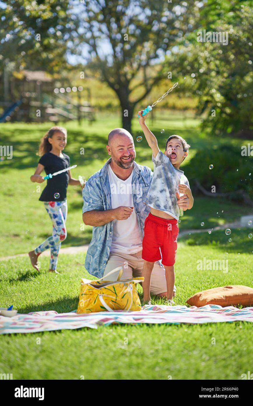 Happy father and son with Down Syndrome playing with bubble wand Stock Photo