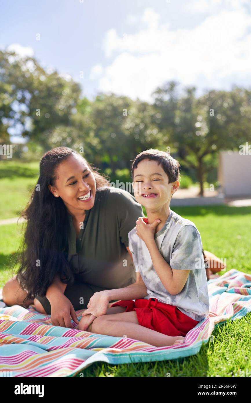 Portrait happy mother and son with Down Syndrome in sunny park Stock Photo