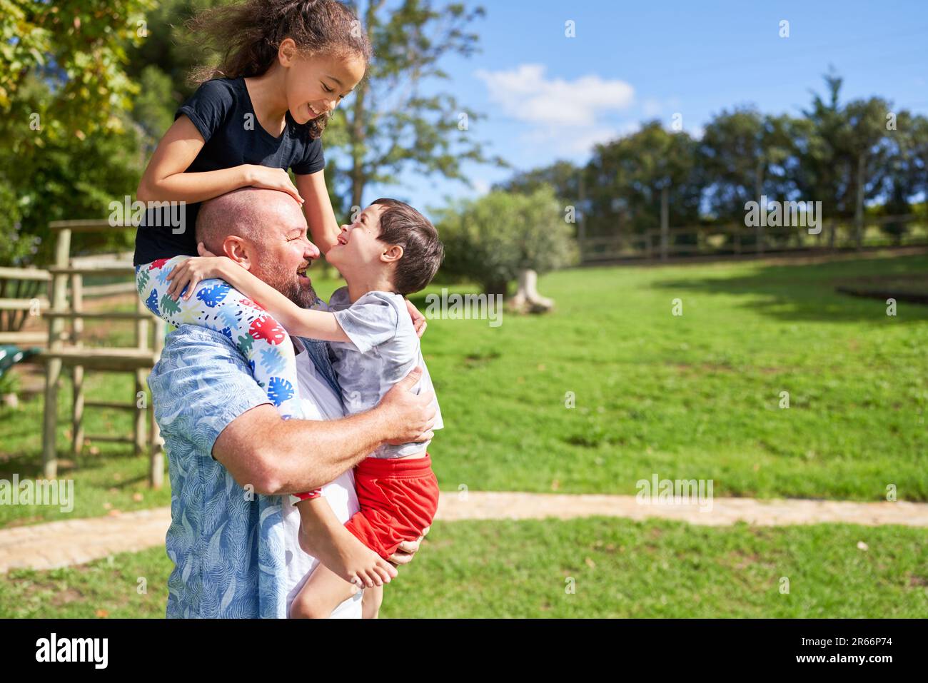 Father holding cute, playful kids in sunny summer park Stock Photo