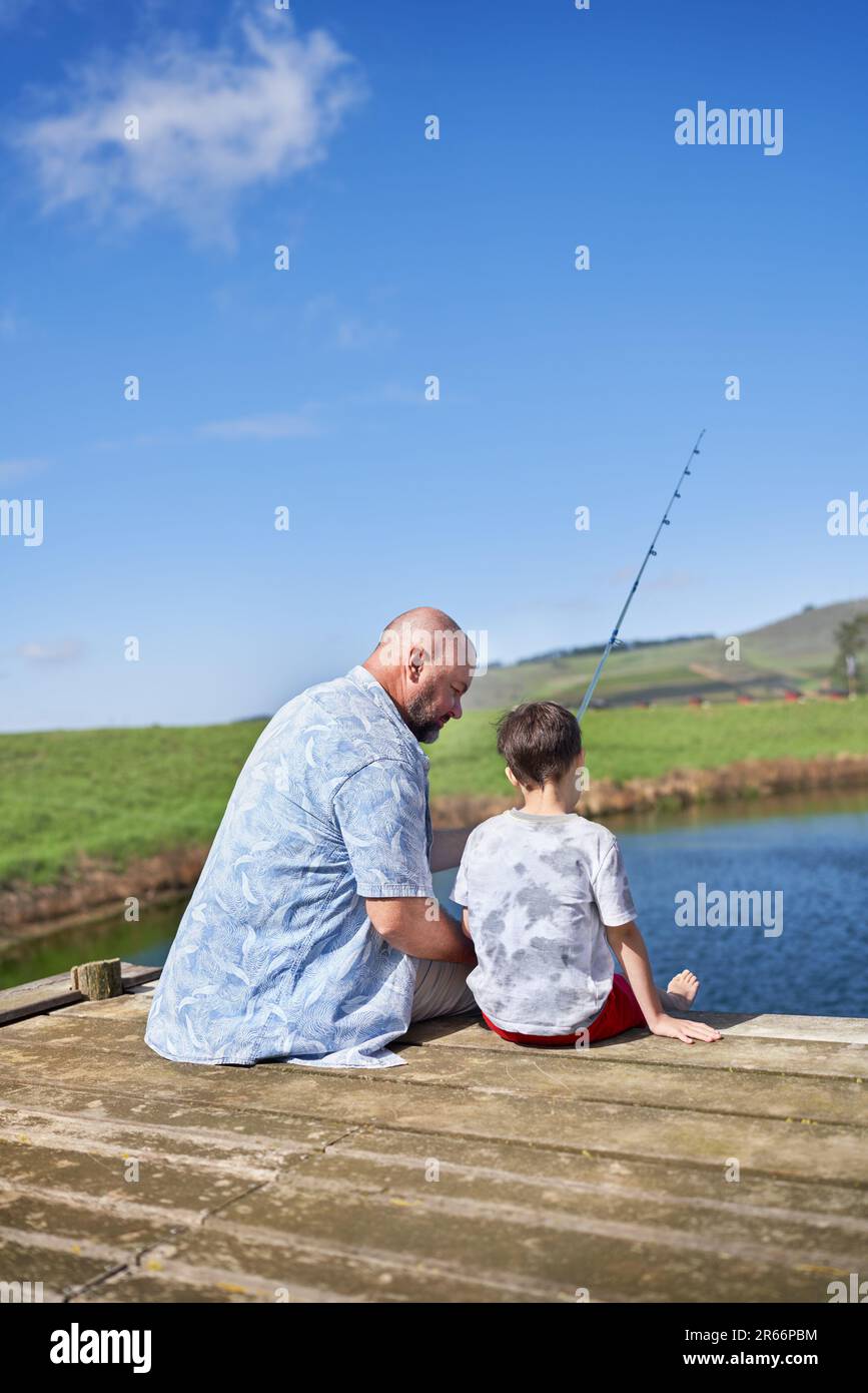 Father and son fishing on sunny summer lakeside dock Stock Photo