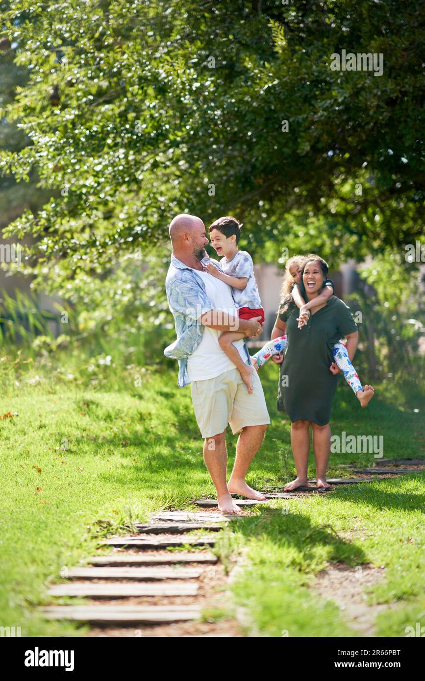 Happy family walking on footpath in sunny summer park Stock Photo