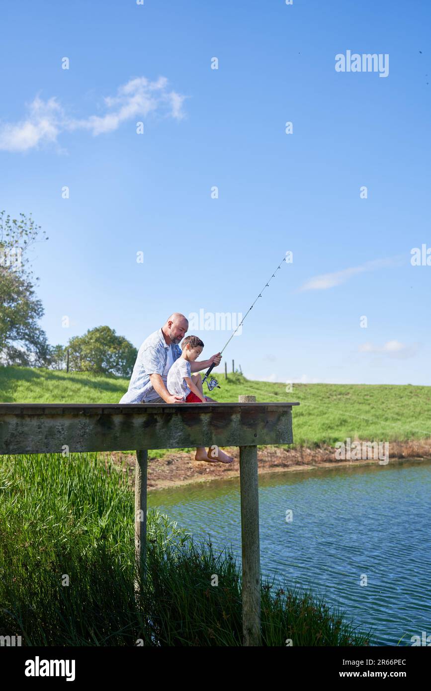 Father and son fishing on sunny summer lakeside dock Stock Photo