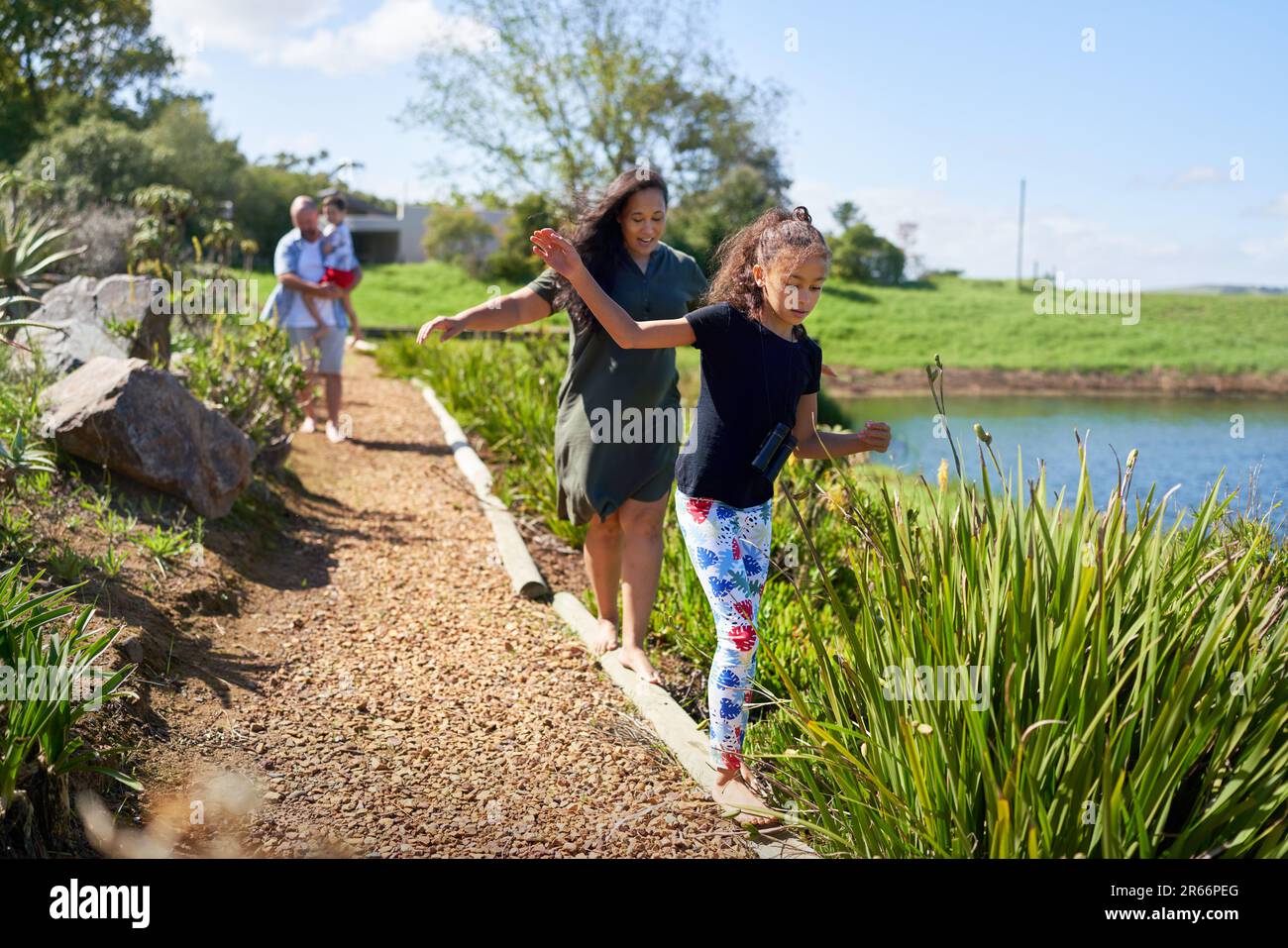 Mother and daughter balancing, walking on footpath logs Stock Photo