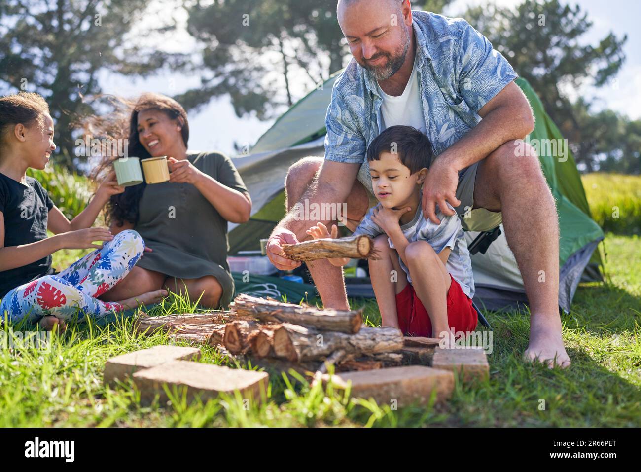 Father and son with Down Syndrome stacking firewood at campsite Stock Photo