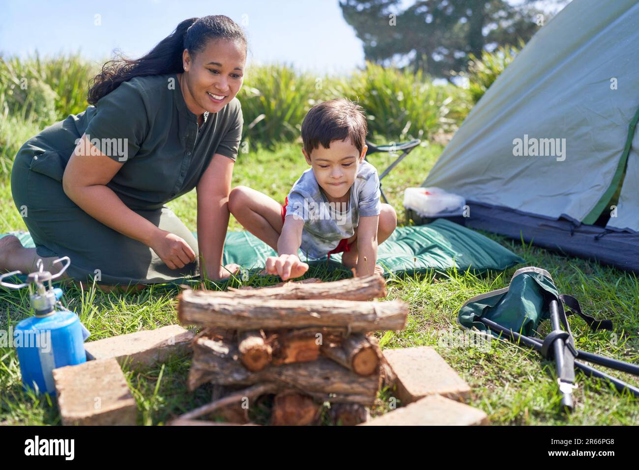 Mother and son with Down Syndrome stacking firewood at campsite Stock Photo