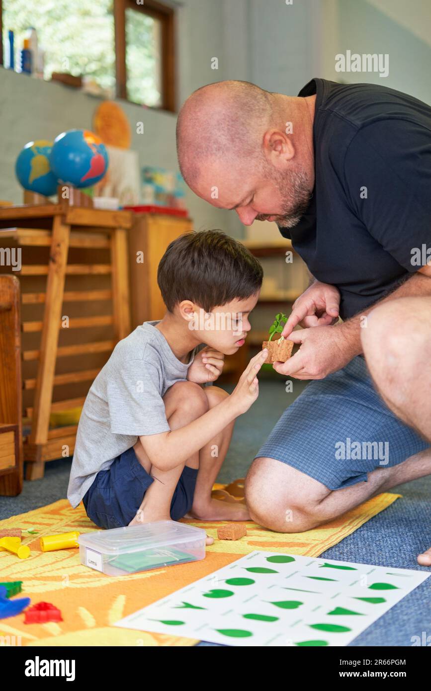 Father teaching son with Down Syndrome about plants at home Stock Photo