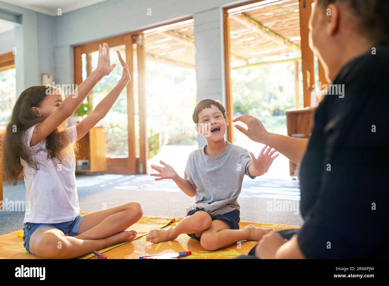 Happy boy with Down Syndrome playing on floor with family Stock Photo