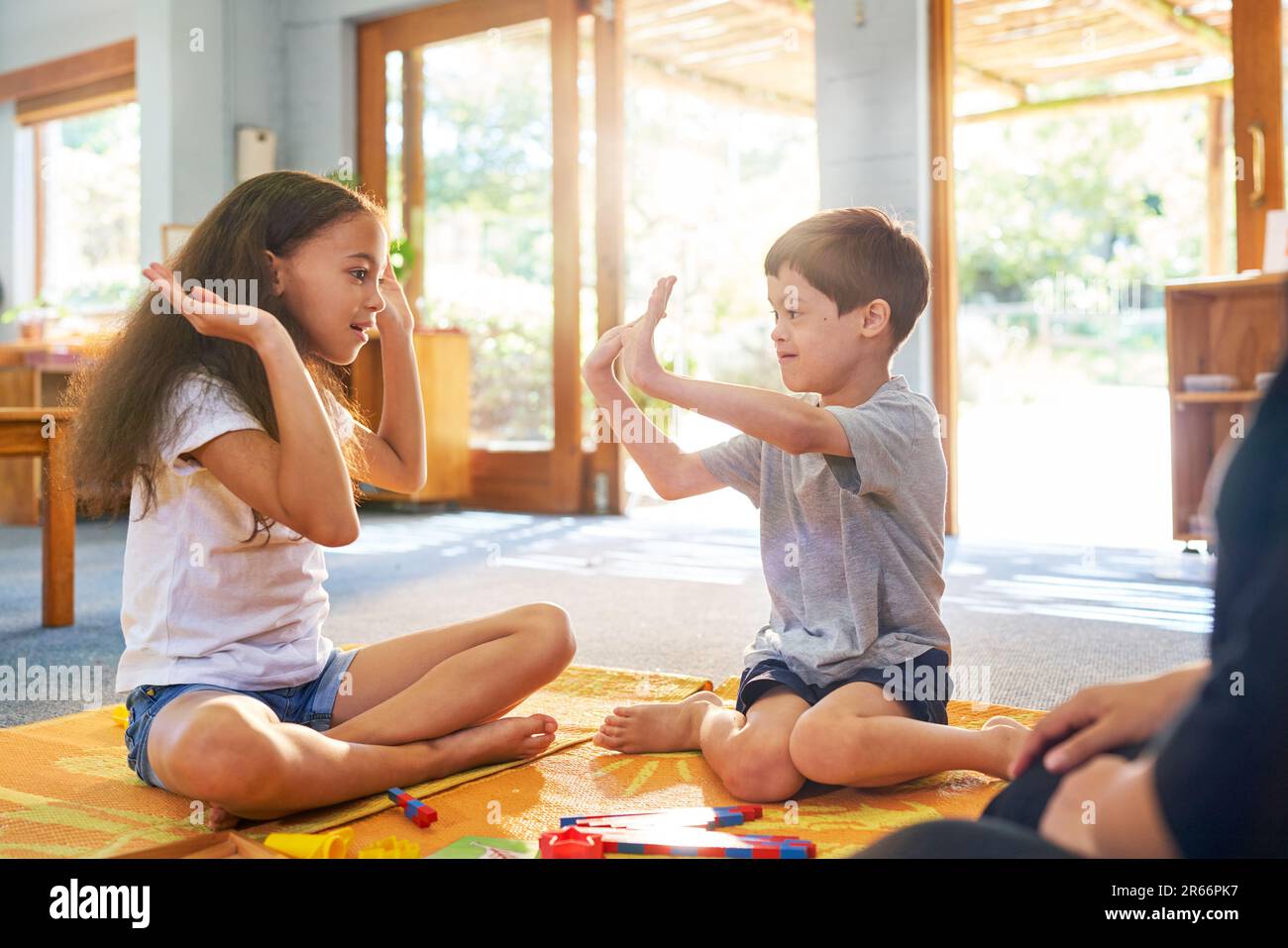 Sister playing clapping game with brother with Down Syndrome at home Stock Photo
