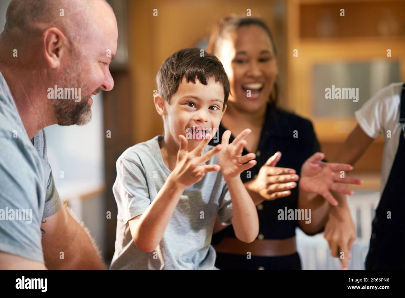 Portrait happy boy with Down Syndrome clapping with family Stock Photo