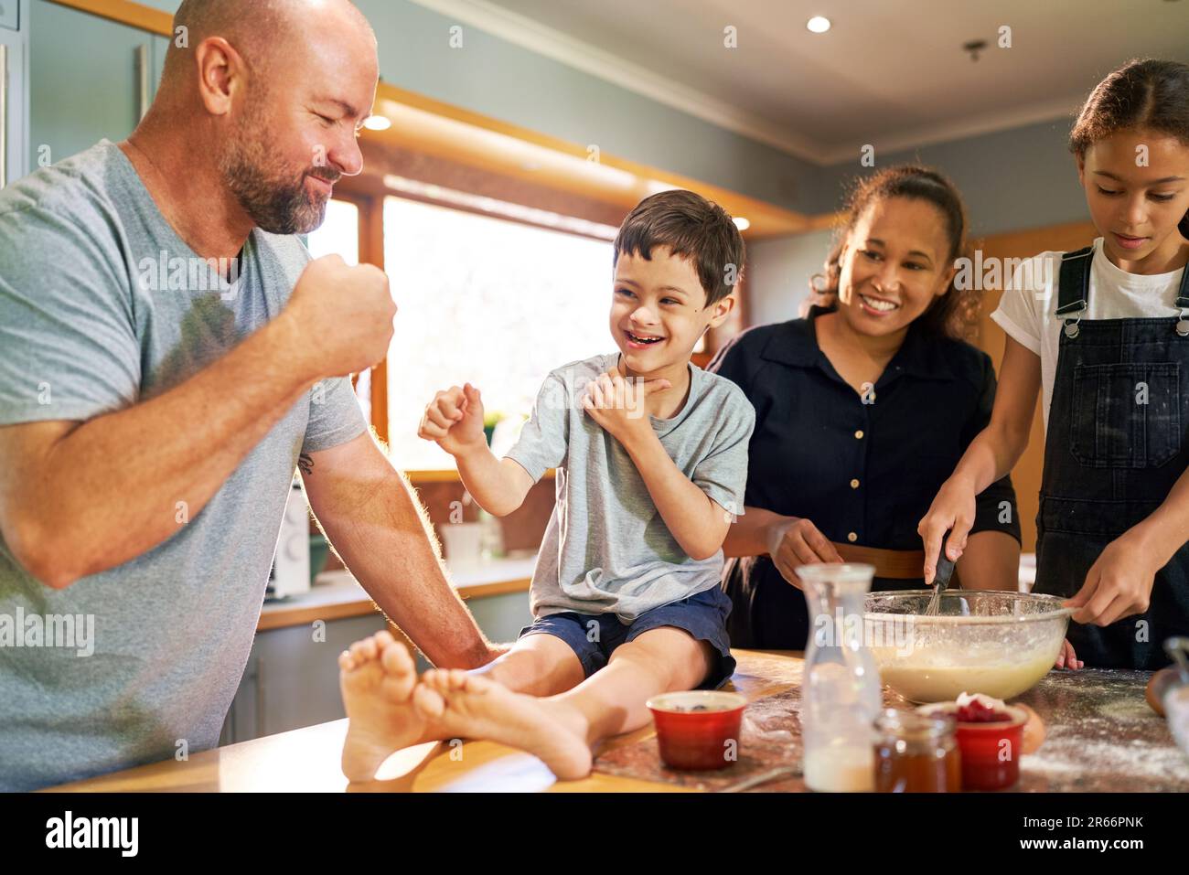 Happy boy with Down Syndrome fist bumping father in kitchen Stock Photo