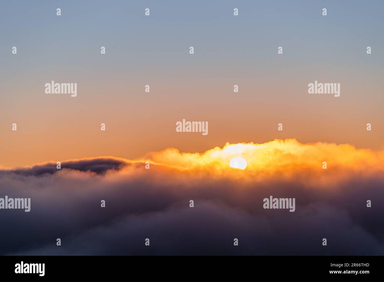 A stunning sunset is visible in the sky, with clouds illuminated in a