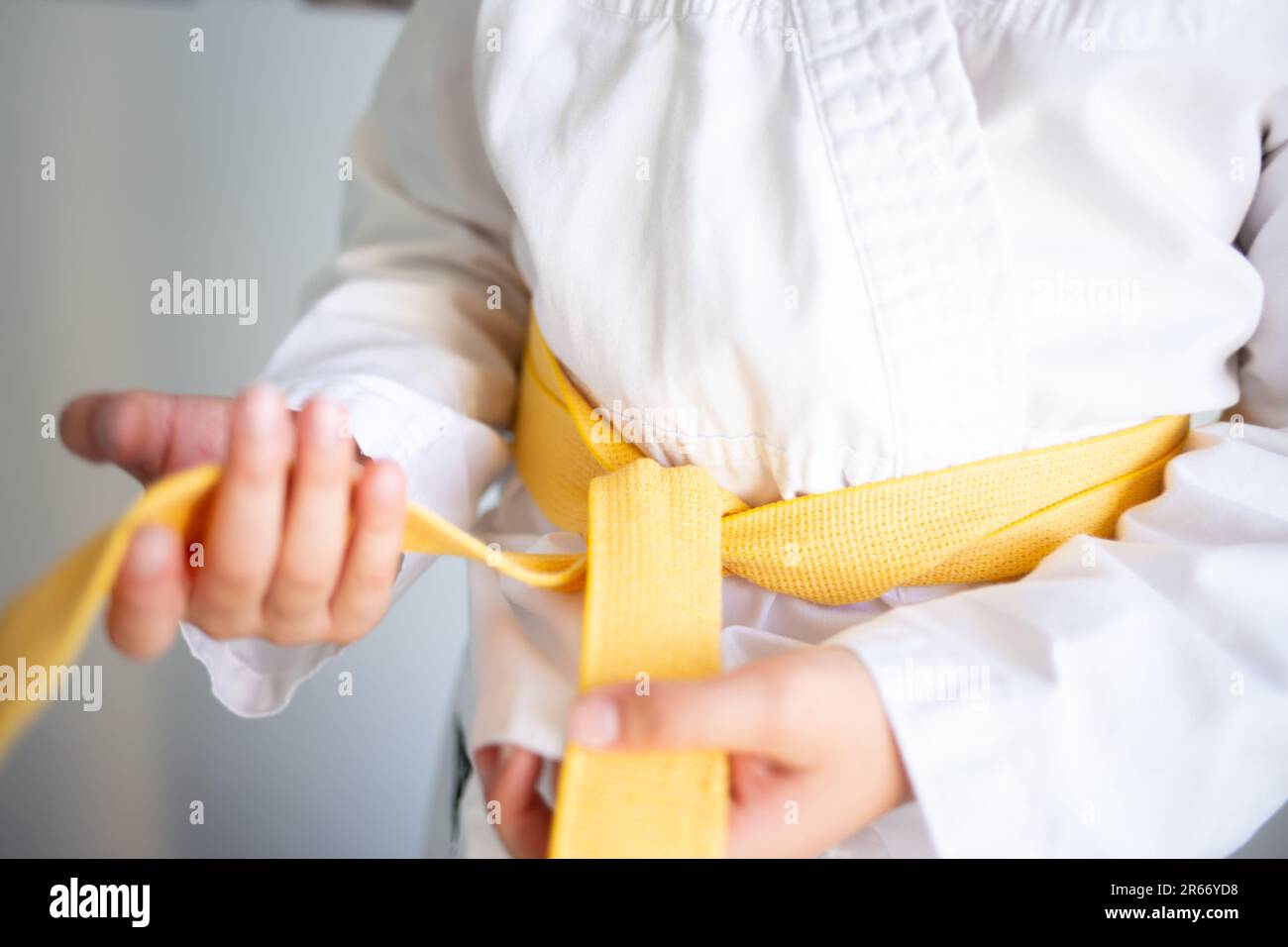 hands tying a yellow belt in judo, soft focus blurred details, kids sport and physical education