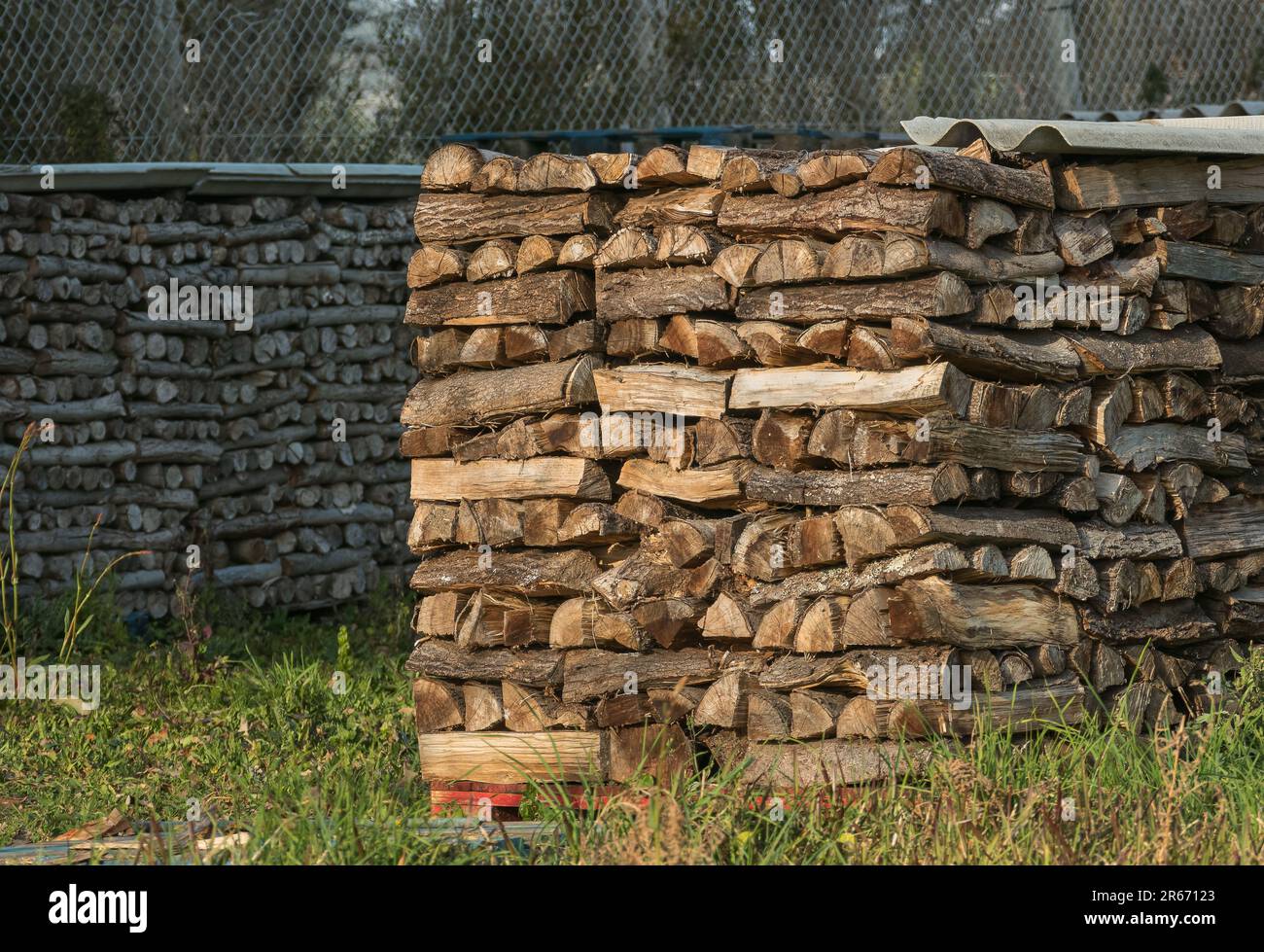 firewood stacked and covered ready to be burned in outdoor fireplace Stock Photo