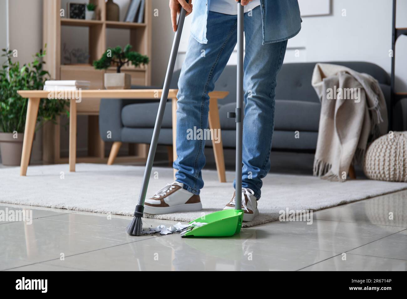 Young man sweeping floor with broom at home Stock Photo