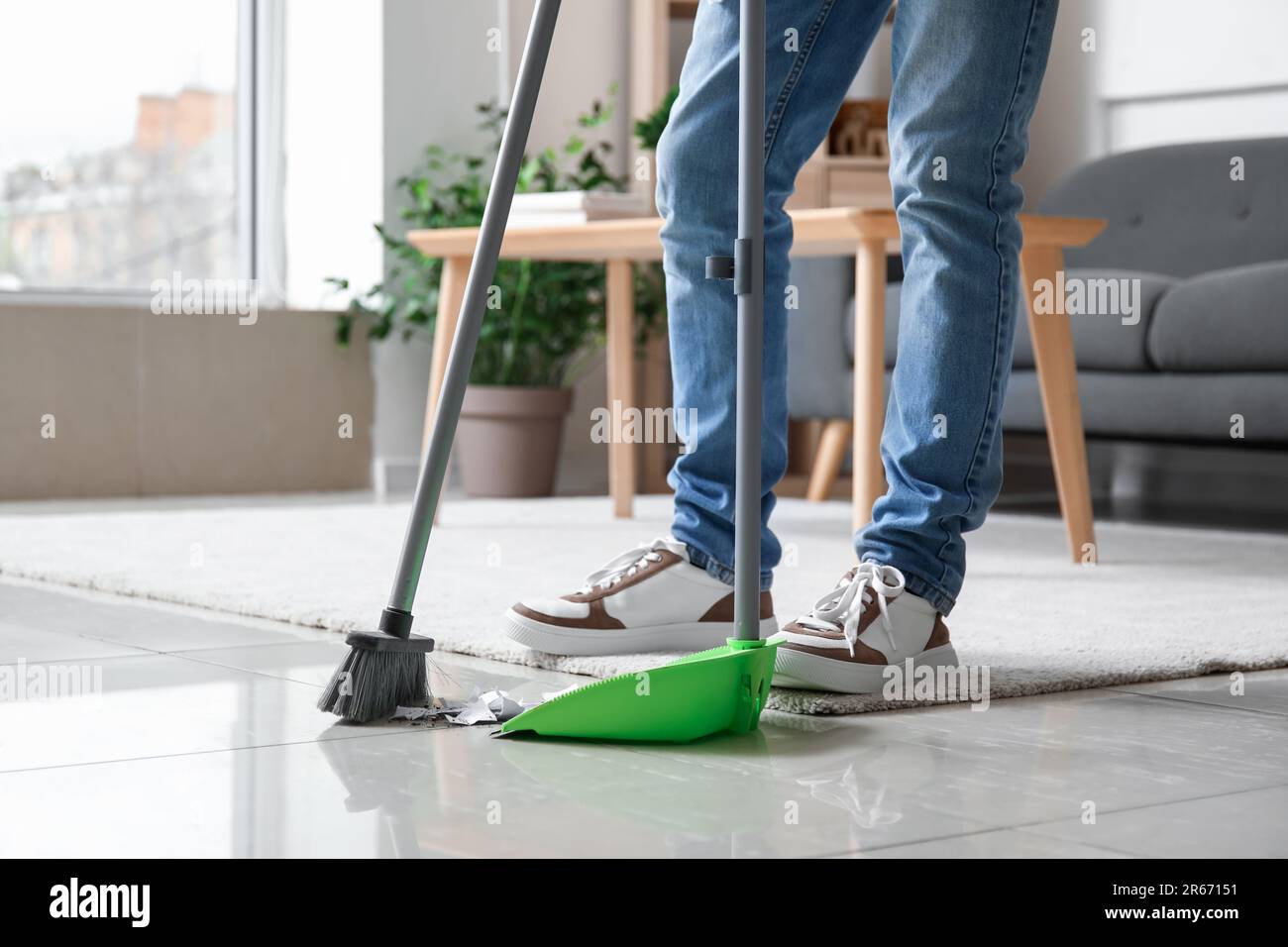 Young man sweeping floor with broom at home Stock Photo