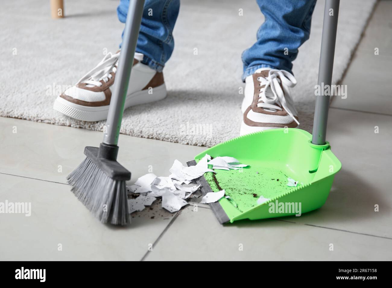 Young man sweeping floor with broom at home, closeup Stock Photo