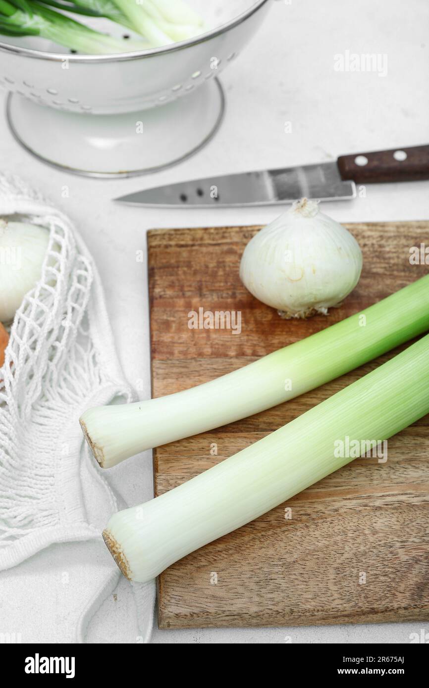 Wooden board and colander with different kinds of onion on white ...